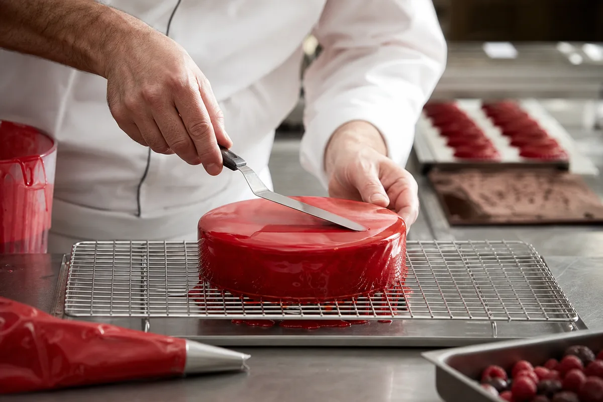 Pâtissier glaçant des entremets dans un laboratoire de pâtisserie artisanale française